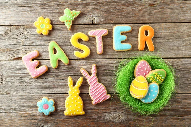 Colorful Easter cookies shaped like letters, eggs, and bunnies on rustic wooden background